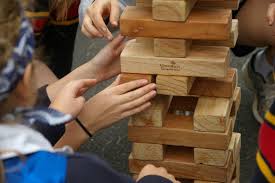 image shows people putting block of wood together to create a tower