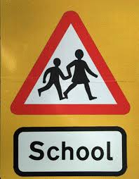 A roadway school sign with a red triangle and child icons. Universal Design for Learning.
