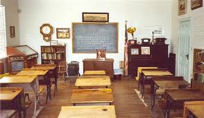 picture of empty classroom showing wooden desks and a small blackboard. Examples of universal design policy.