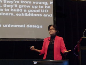 Siam Imm in a bright pink jacket making her presentation on barrier free to universal design Singapore's experience.