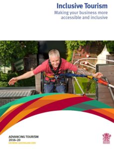 Front cover of Queensland inclusive tourism guide showing a man in a red shirt with his arms outstreched
