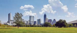 landscape view of tower buildings in the distance and green parkland in the foreground