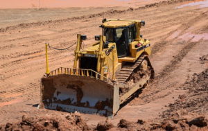 A yellow bulldozer is pictured against bare orange ground