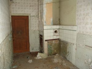Bathroom in an old house has been stripped and bare walls and old tiles remain