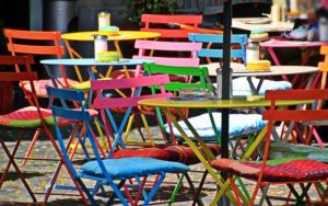 brightly coloured simple folding chairs in an outdoor cafe setting.