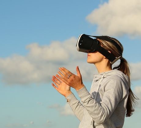 A young woman is wearing a pair of virtual reality goggles and looking towards the sky.