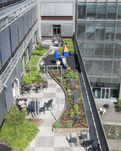 An aerial view of a hospital courtyard showing gardens, seating and children's play equipment.