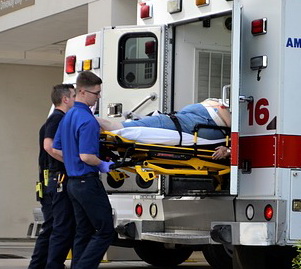 Two ambulance officers push a patient into the ambulance.