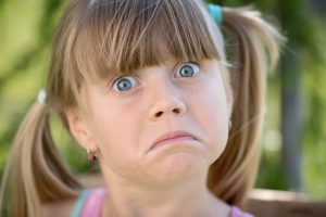 A young girl is wide-eyed with a drooping mouth as is she is about to be unhappy. Autism and building design.