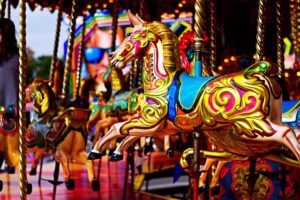 A brightly coloured horse on a carousel ride in a theme park. 