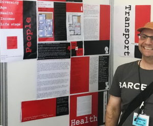 Nicholas Loder stands by his poster at the Barcelona ICTH conference. It is displayed in black and red.