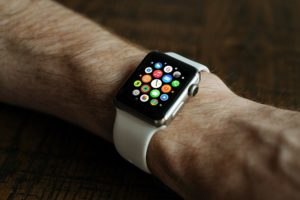 On a man's wrist is a Apple Smart Watch. The face has multiple coloured dots.