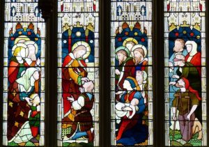 Four panes of a church stained glass window depict different people needing help.