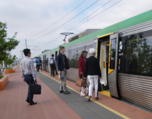 Passengers are getting on a train in Perth. There is a yellow plate that covers the gap between the platform and carriage.