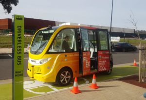 A yellow automated driverless vehicle is parked by the footpath.