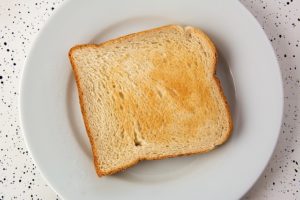 one slice of toast sits on a small white place.