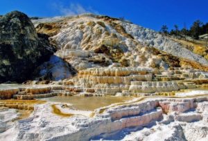 Mammoth Hot Springs. Rocky terraces formed by yellow sulphur stand in front of a bright blue sky. Universal Design for Yellowstone.
