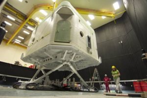 A view of the simulator from ground level. Two people stand nearby and they look very small in comparison.