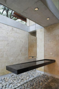 A long black sink shaped like a shelf hangs longways from the wall. The backwall is full length window and it is difficult to see the tap. It looks very modern.
