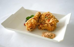 Three pieces of fried chicken are placed in a white cardboard box.