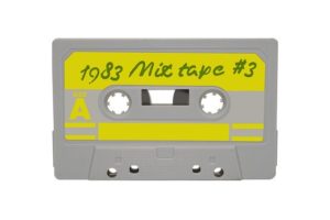 A grey coloured music cassette tape with a yellow label marked, '1983 Mix Tape #3.'