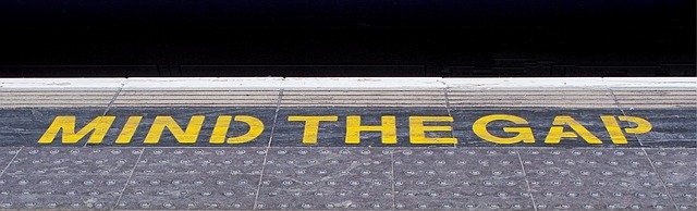 Train station platform edge with the words in yellow, "Mind the gap".