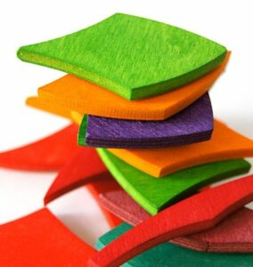 A pile of brightly coloured squares sit untidily on top of each other. The colours are very bright. Creating independence with colour. 