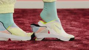The Nike shoe is fashioned with pastel coloured sections. The picture shows a person taking their foot out of the shoe.