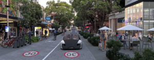 A streetscape of the future with street plantings, outdoor eating and a driverless car in a 30 kph zone.