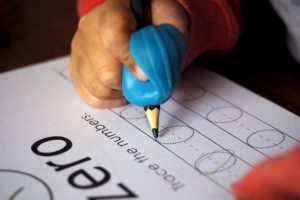 A student writing with the aid of a pencil grip.