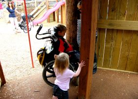Two children, one in a wheelchair, enter a cubby area.