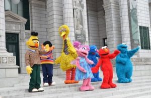 Sesame Street characters dancing in the street.