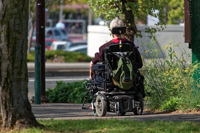 A person in a powered wheelchair riding along the footpath.