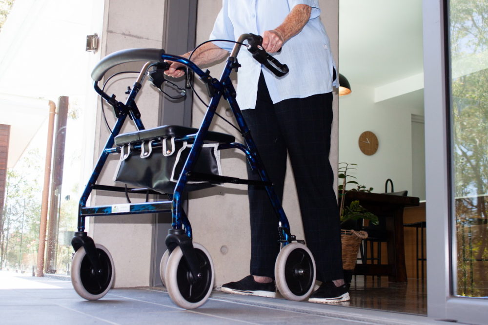 A person with a four-wheeled walker rolls over the level threshold.