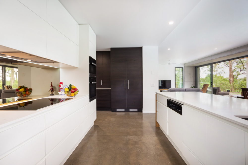 Kitchen with white benches contrasting with the light brown floor.