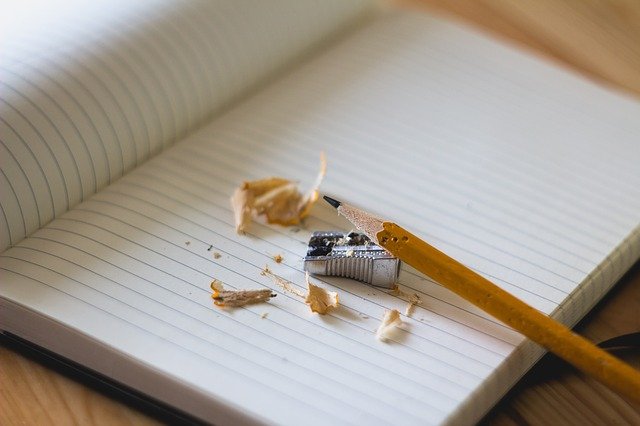 An empty page in a notebook with a pencil and sharpener. Doing plain language is a process