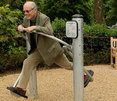 A man is enjoying himself on exercise equipment in a play space for older adults.