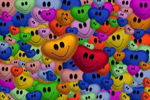 Many coloured heart shapes with black eyes and smiles indicate diversity. Telling stories for inclusion.