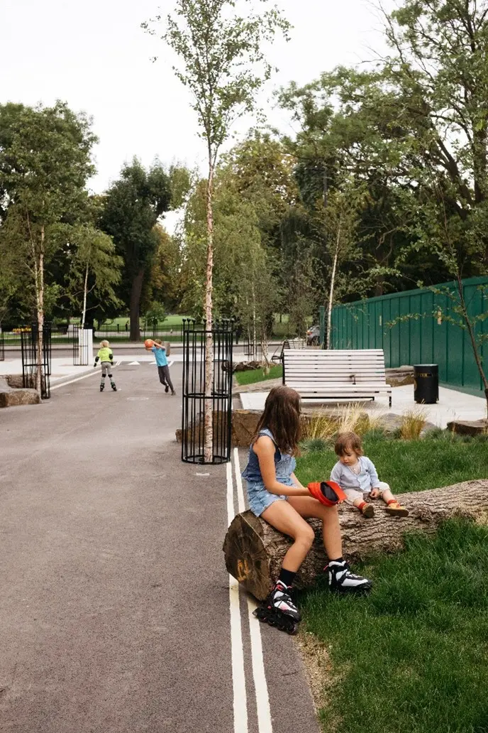 The street has a wide nature strip alongside the footpath with seating, grassed area and a log. Hackney Play Street design by Muf Architecture.