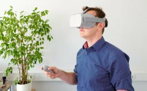 A man in a blue shirt is wearing virtual reality goggles and is holding a controller in his hand. This is part of exploring Human centred design 