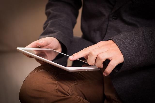a man is reading a tablet device.