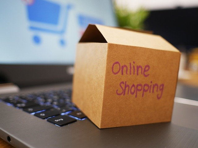 A small cardboard box sits across a keyboard. The words on the box say online shopping. 