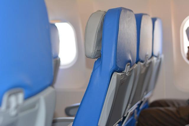 Close up of a row of aircraft seats which are bright blue with grey backs. 