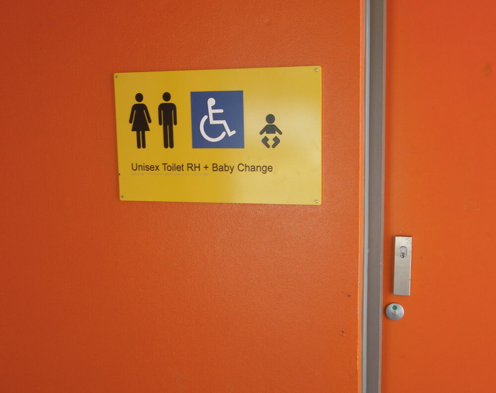 On orange door with a sign saying Unisex Toilet and baby change with icons to match.