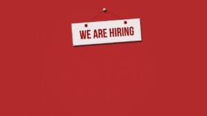 A deep red background to a sign saying "we are hiring".