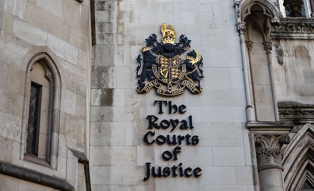 Photo of the sign on the grey stone building of The Royal Courts of Justice. 
