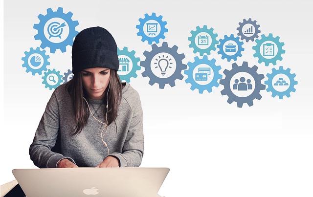 A young woman wearing a black beanie sits in front her her laptop. Behind her are icons of cog wheels indicating technology. Age and gender bias in computer science. 